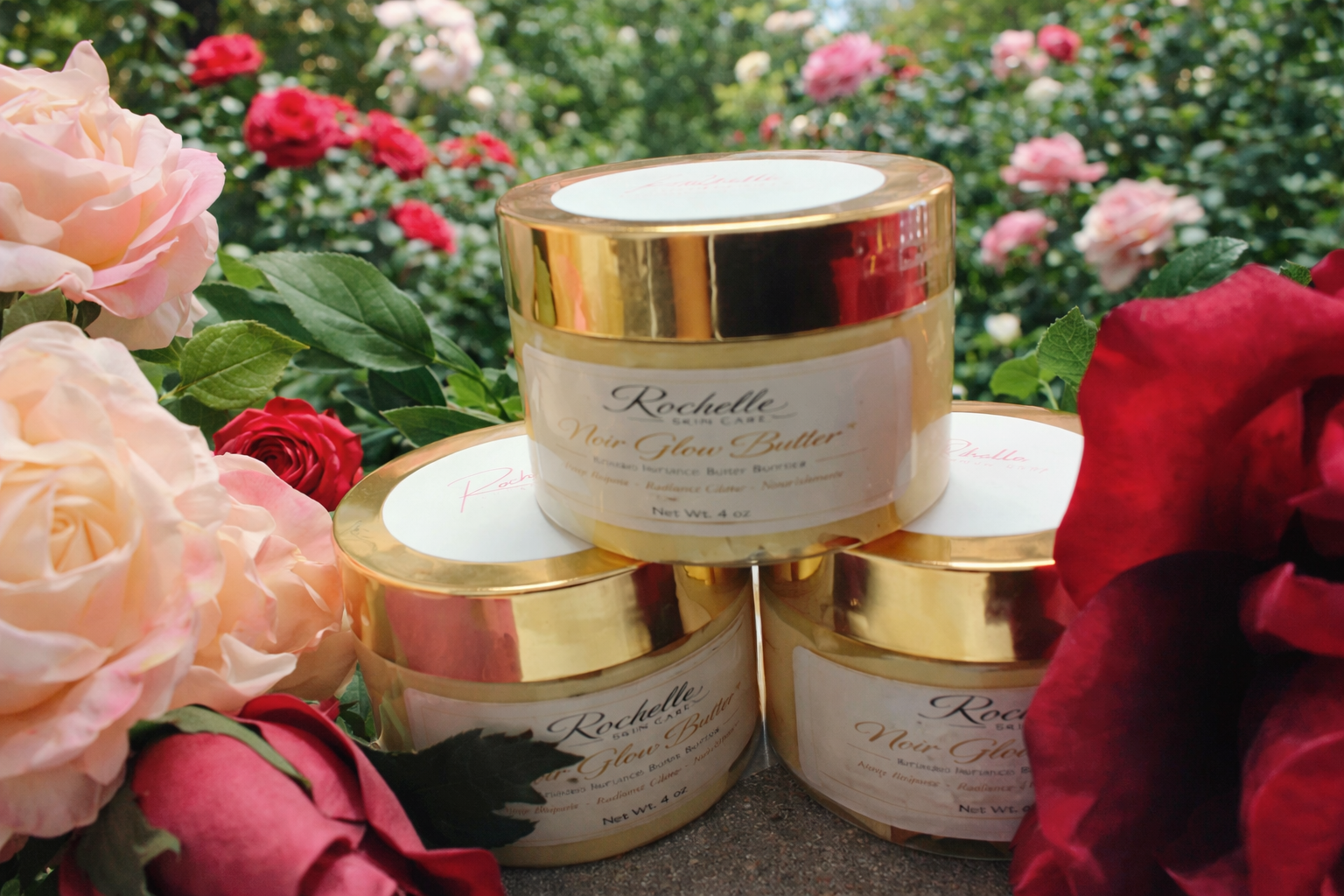 Jars of Rochelle Pure Glow Butter with flowers in the background